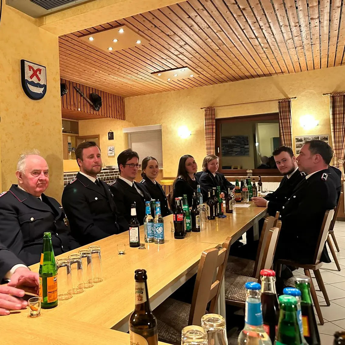 8 Feuerwehrmänner/Frauen sitzen gemeinsam am Tisch